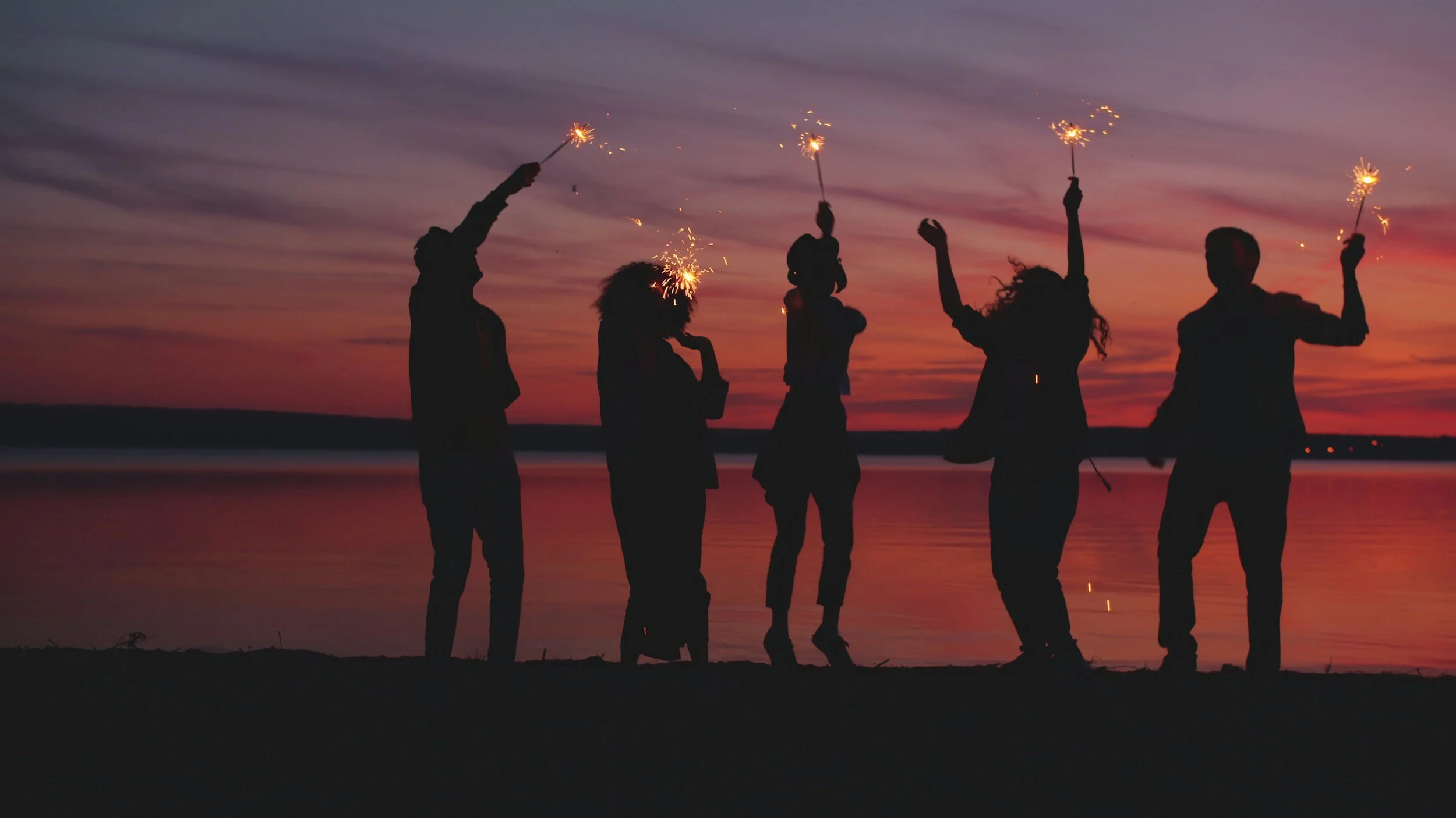 Scenic landscape of a lake surrounded by rolling hills and mountains, with cloudy sky overhead.