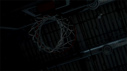 A basketball hoop with a net against a dark background, touring the Nike stadium in New York.