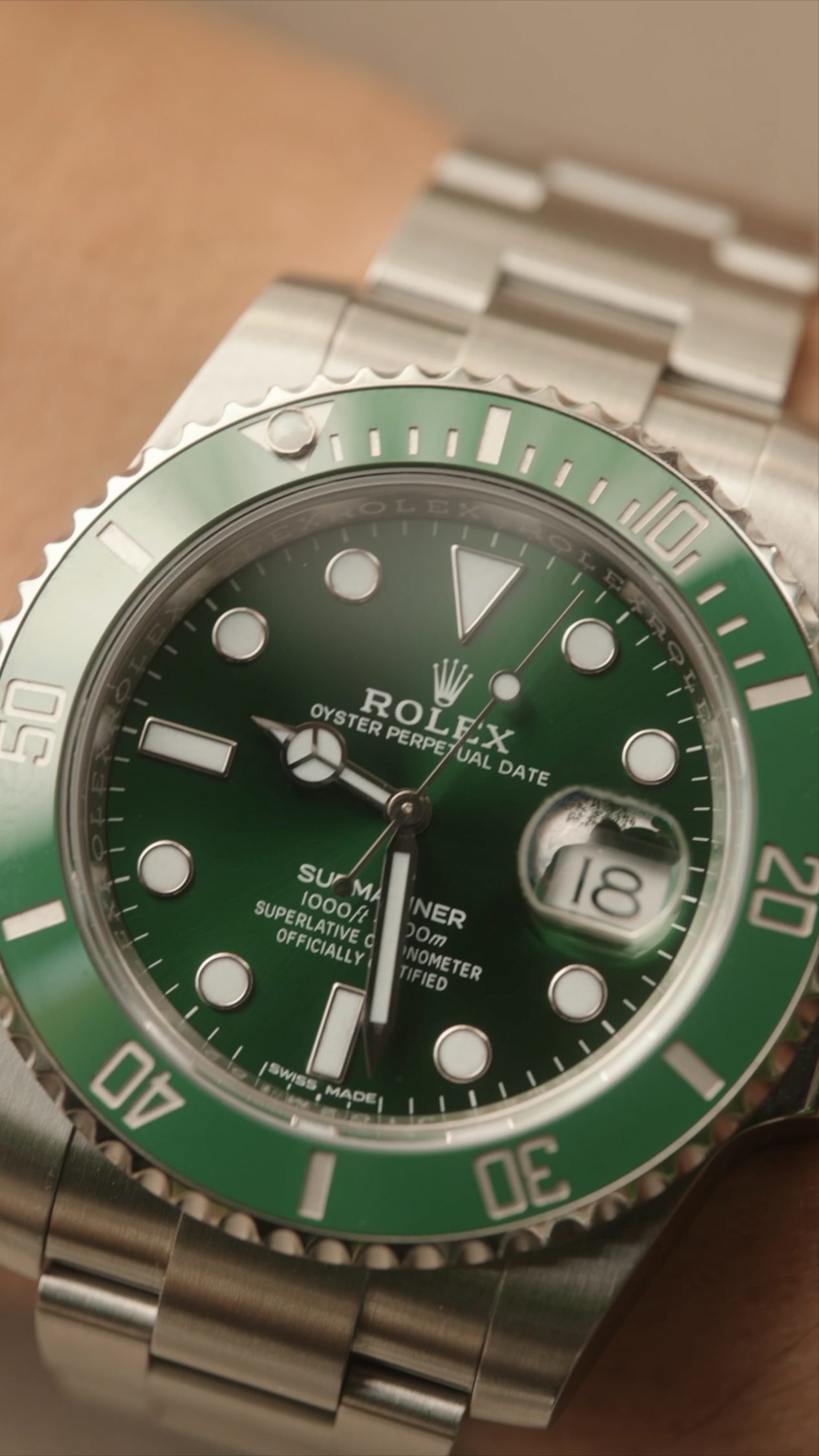 Close-up of a green Rolex Submariner watch showing the time, date, and a rotating bezel.