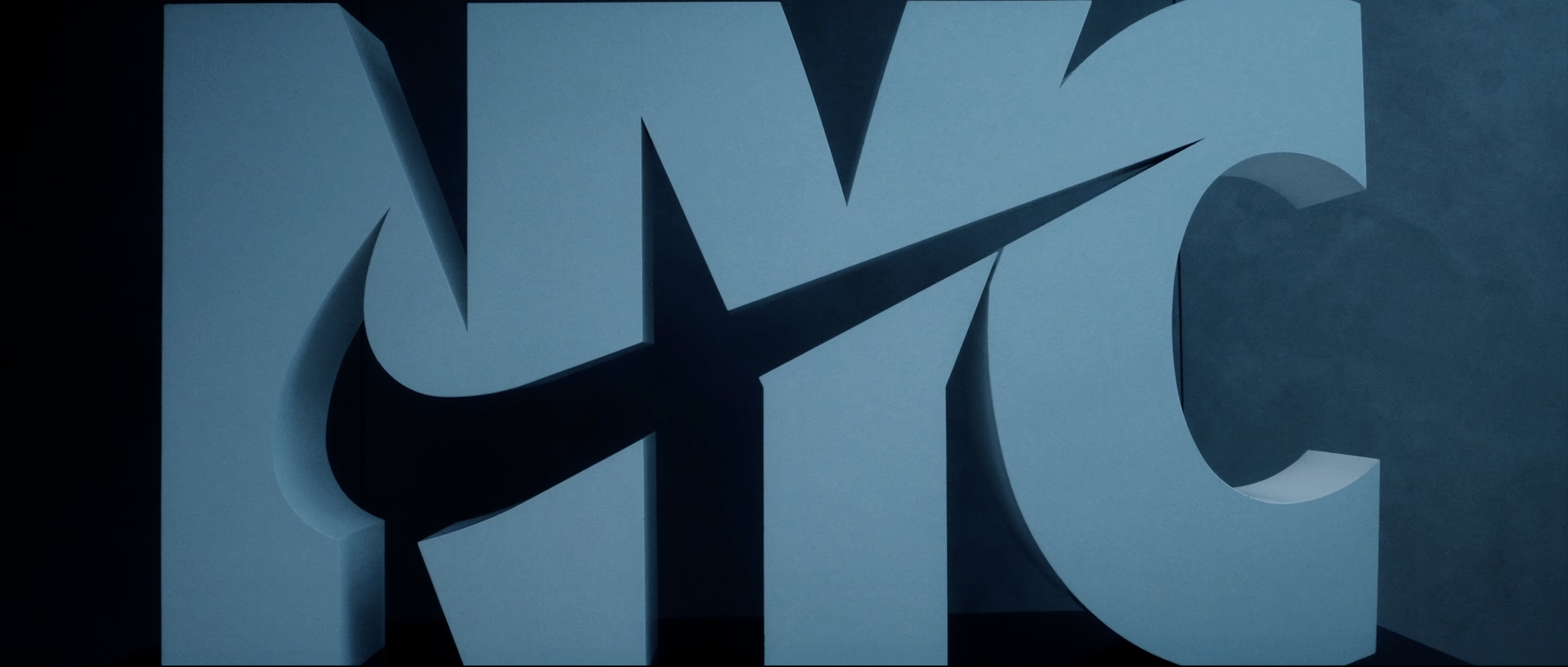 A large, light blue 3D Nike logo with a swoosh symbol, mounted on a dark background.