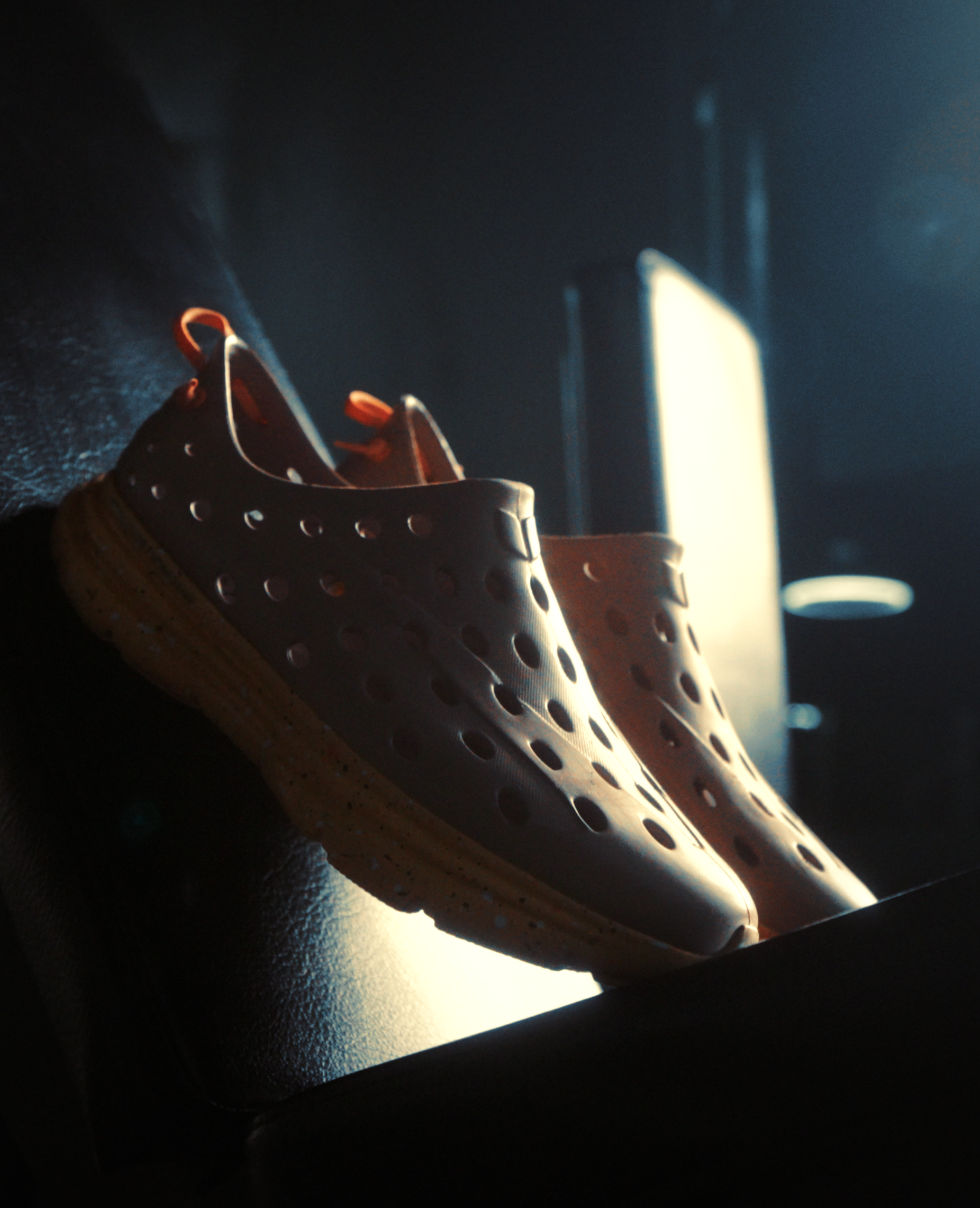 Upside-down shoes on a car dashboard with sunlight shining through a window in the background.