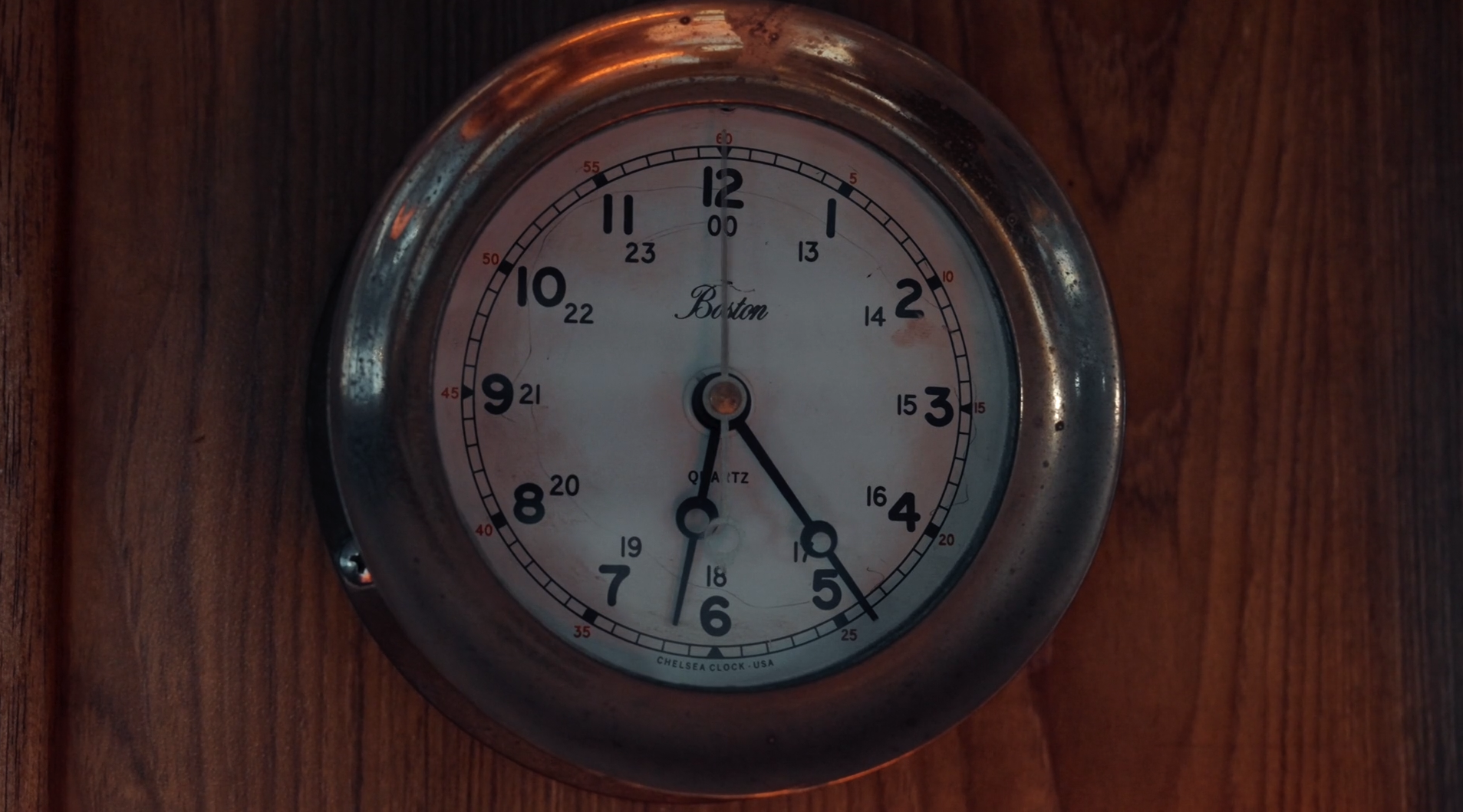 A vintage Chelsea clock mounted on a wooden wall showing the time as 4:28.
