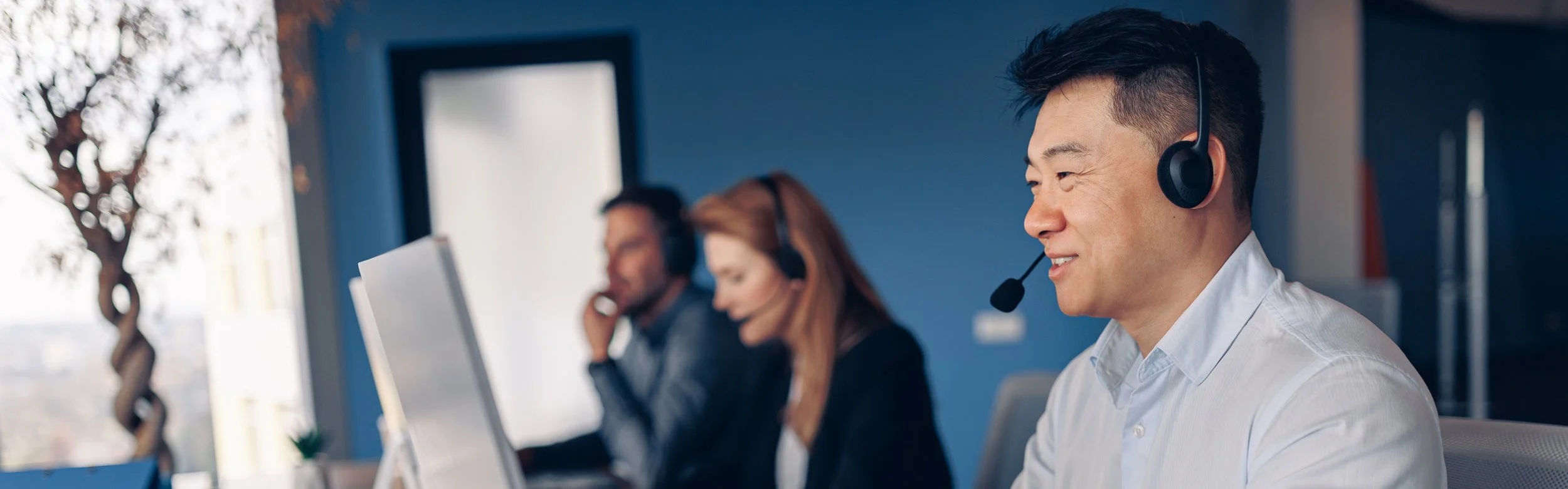 People working at desks with headsets on in an office setting.