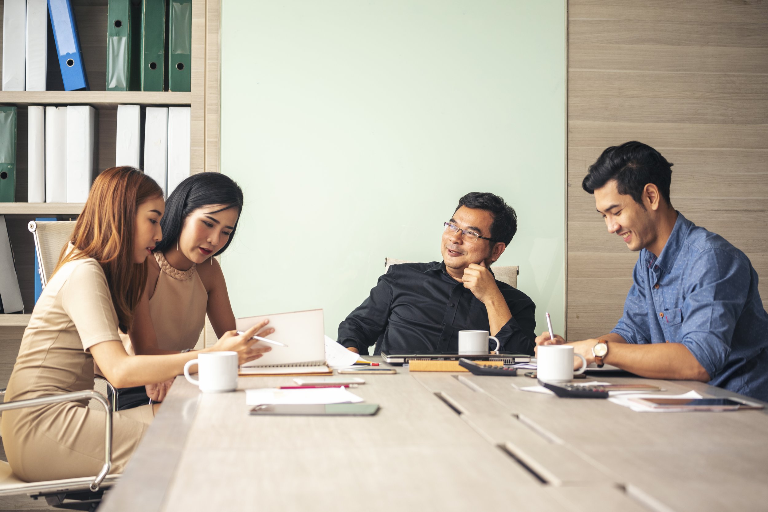 Four people sitting at a conference table having a discussion in a modern office.