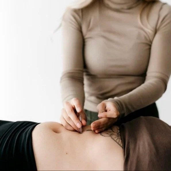 A person in a beige long sleeve shirt is doing cupping therapy on a person's abdomen.