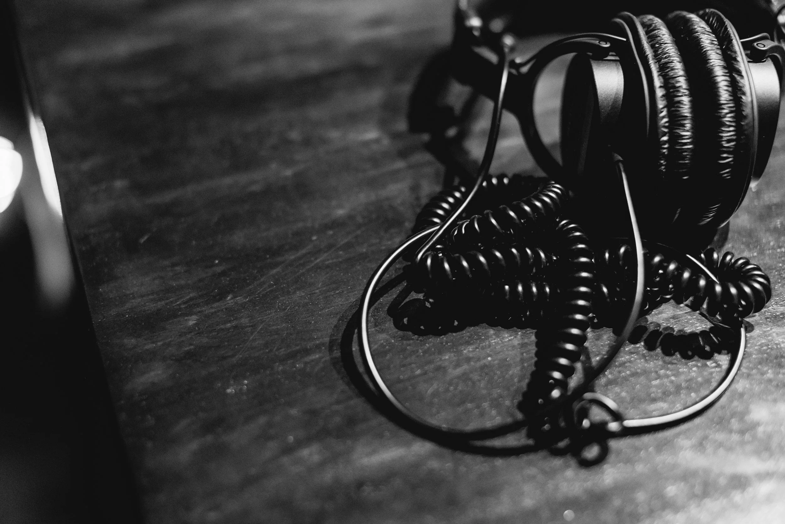 Black over-ear headphones and coiled cable on a dark wooden surface.