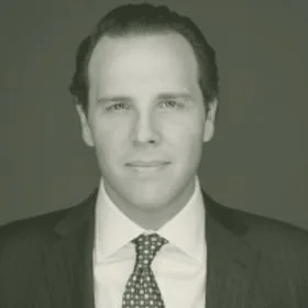 Black and white portrait of a man with short hair wearing a suit and tie, looking at the camera
