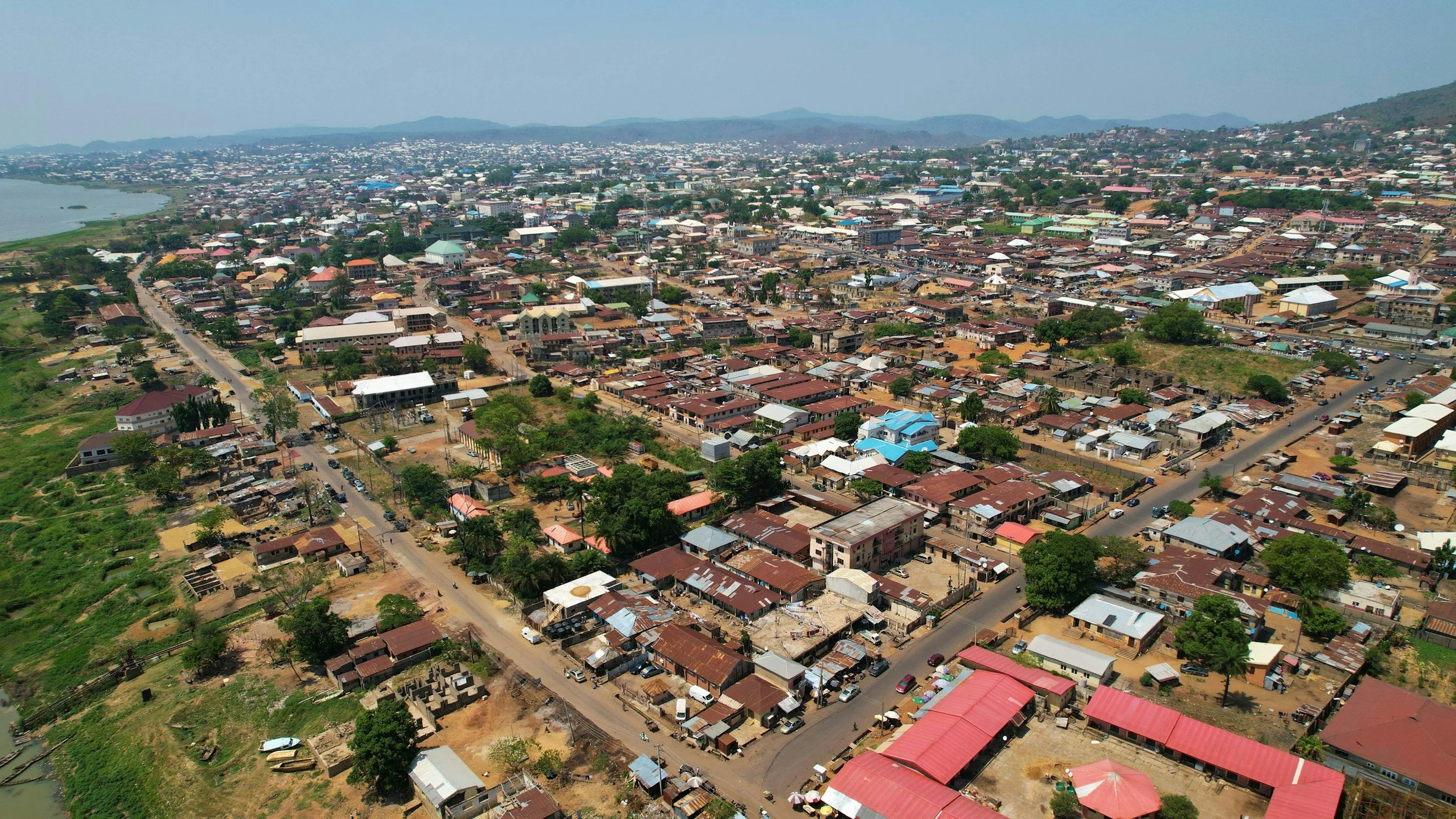 Aerial view of a densely populated city with numerous houses, buildings, and roads, with hills in the background.