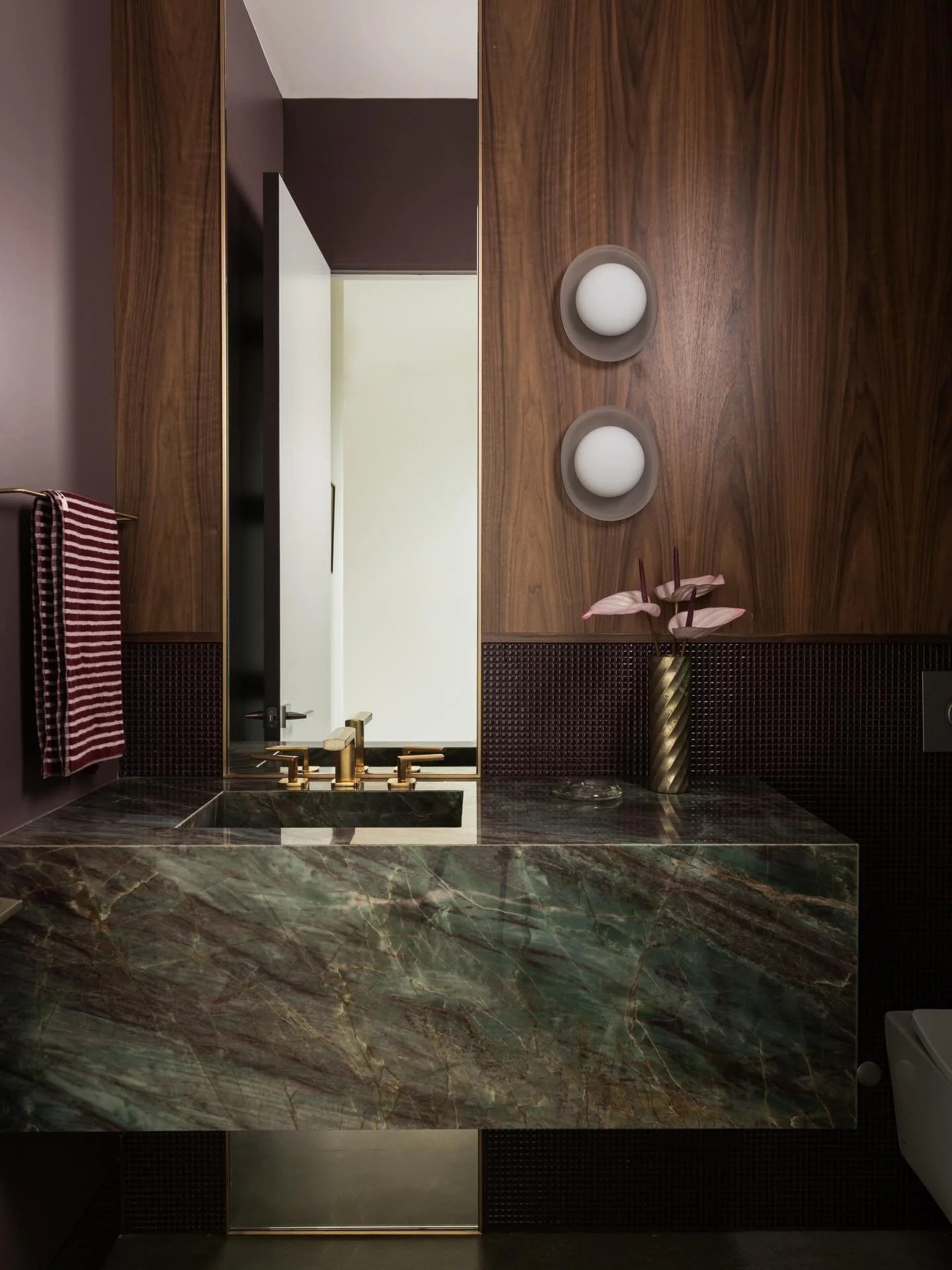 A floor to ceiling mirror flush with walnut and aubergine micro mosaics. Oh and the quartzite- veining of purples, emeralds, and turquoise all of which create quite the vibe upon entering this home. Dare I say, it&rsquo;s giving a bit of &lsquo;70&rs