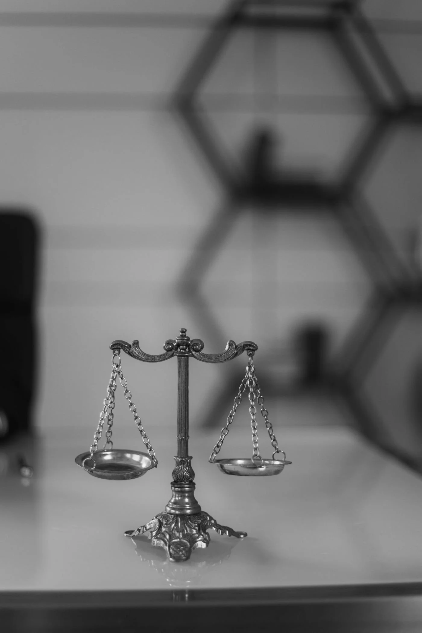 A vintage silver balance scale sits on a desk, symbolizing justice and fairness, with a blurred modern background.