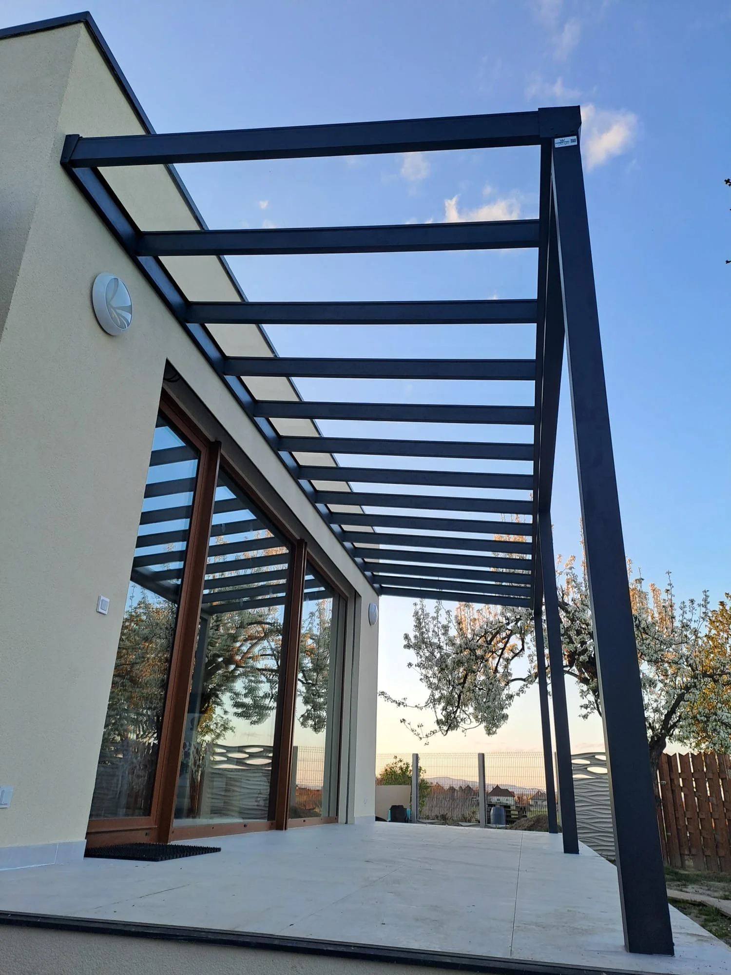 Modern ház terasza antracit alu pergolával, nagy tolóajtós üvegfallal - elegáns alumínium pergola és teraszfedés megoldás