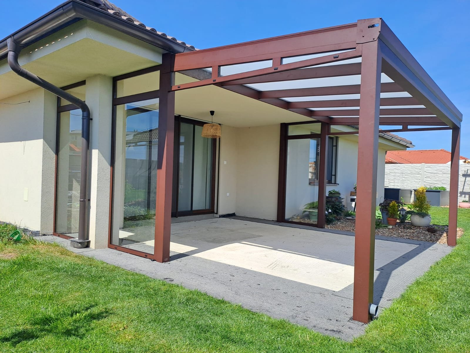 Modern ház üveg teraszfedéssel, tolóüvegezéssel, elegáns, barna üvegtetős pergola alumínium szerkezettel