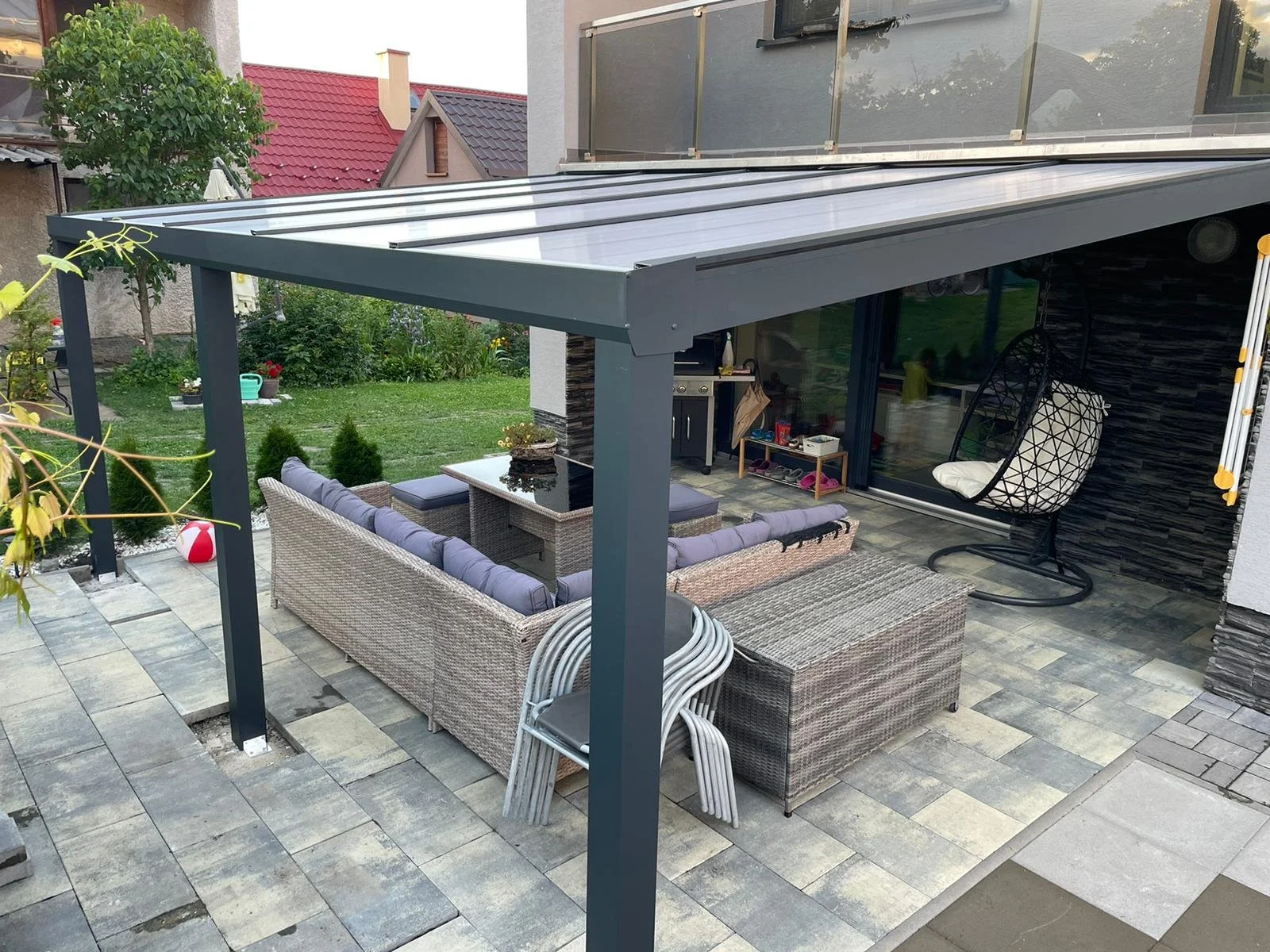 Modern rattan kerti bútorokkal berendezett, pergolával fedett terasz függő hintaszékkel