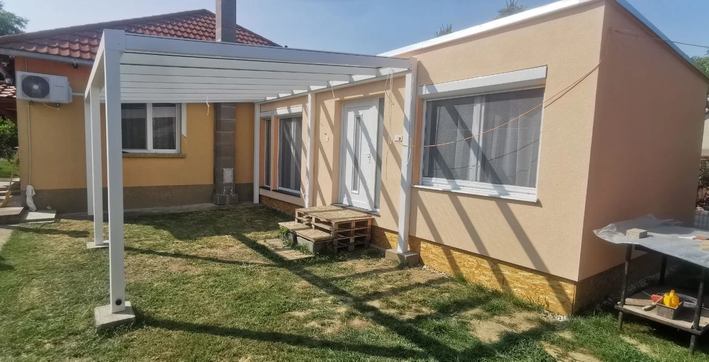 Épülő fehér alumínium pergola családi ház kertjében, zöld gyepes udvaron