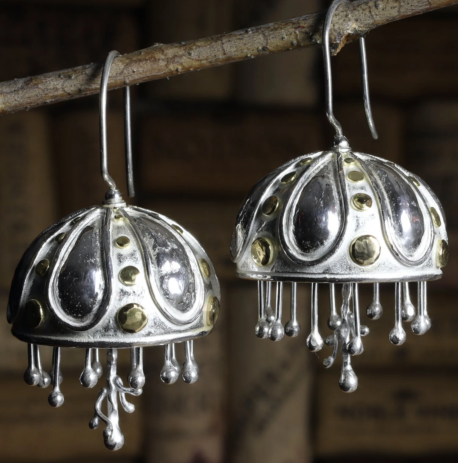 Silver earrings with dangling beaded strands hanging from a rustic wooden branch