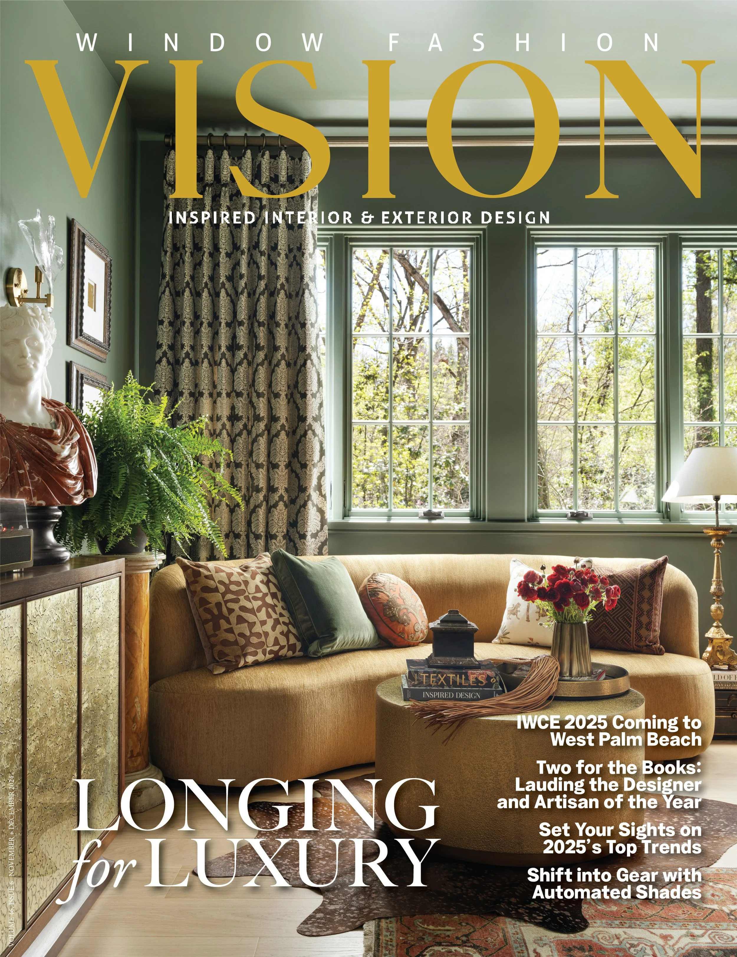 Cover of "Window Fashion Vision" magazine featuring a cozy living room with green walls, large windows with patterned curtains, a yellow sofa with decorative pillows, a sideboard with a sculpture and plants, a round coffee table with books and a vase of red flowers, and a lamp, during daytime.