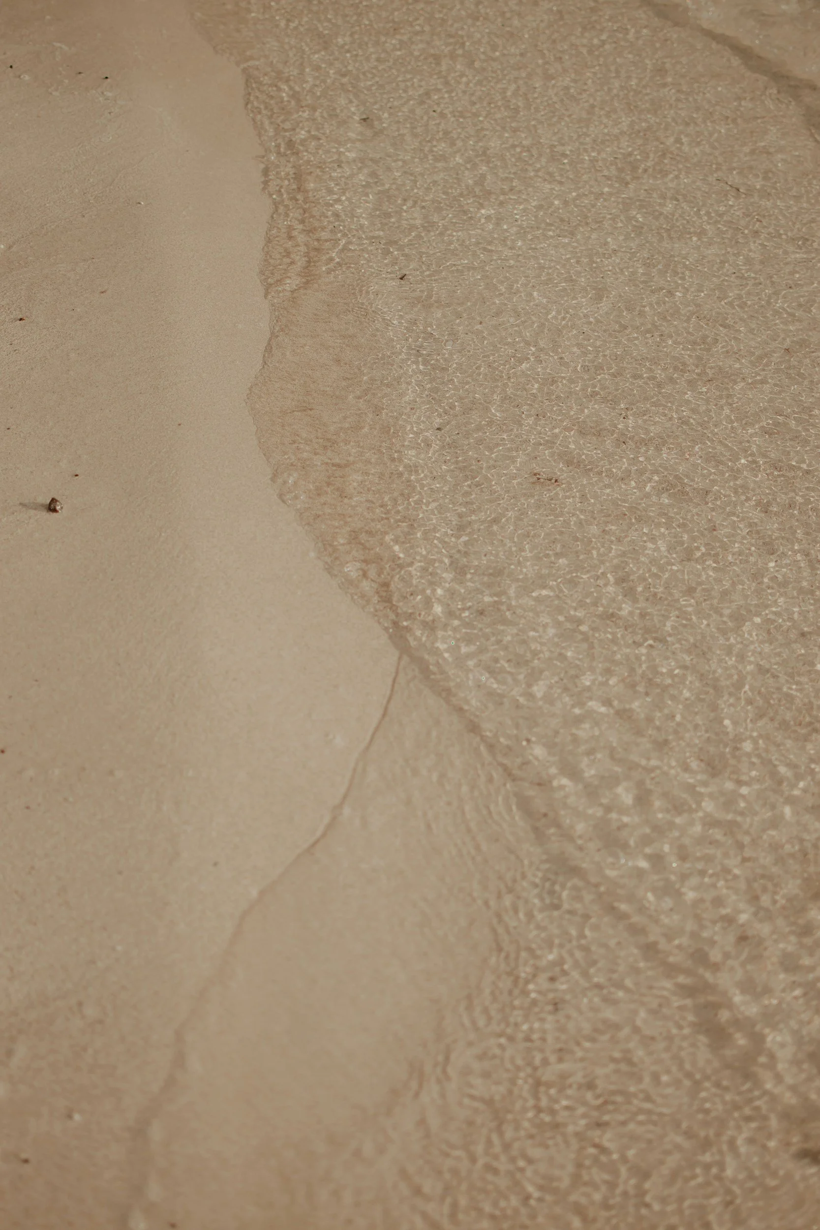 Close-up of a sandy beach with gentle waves washing onto the shore.