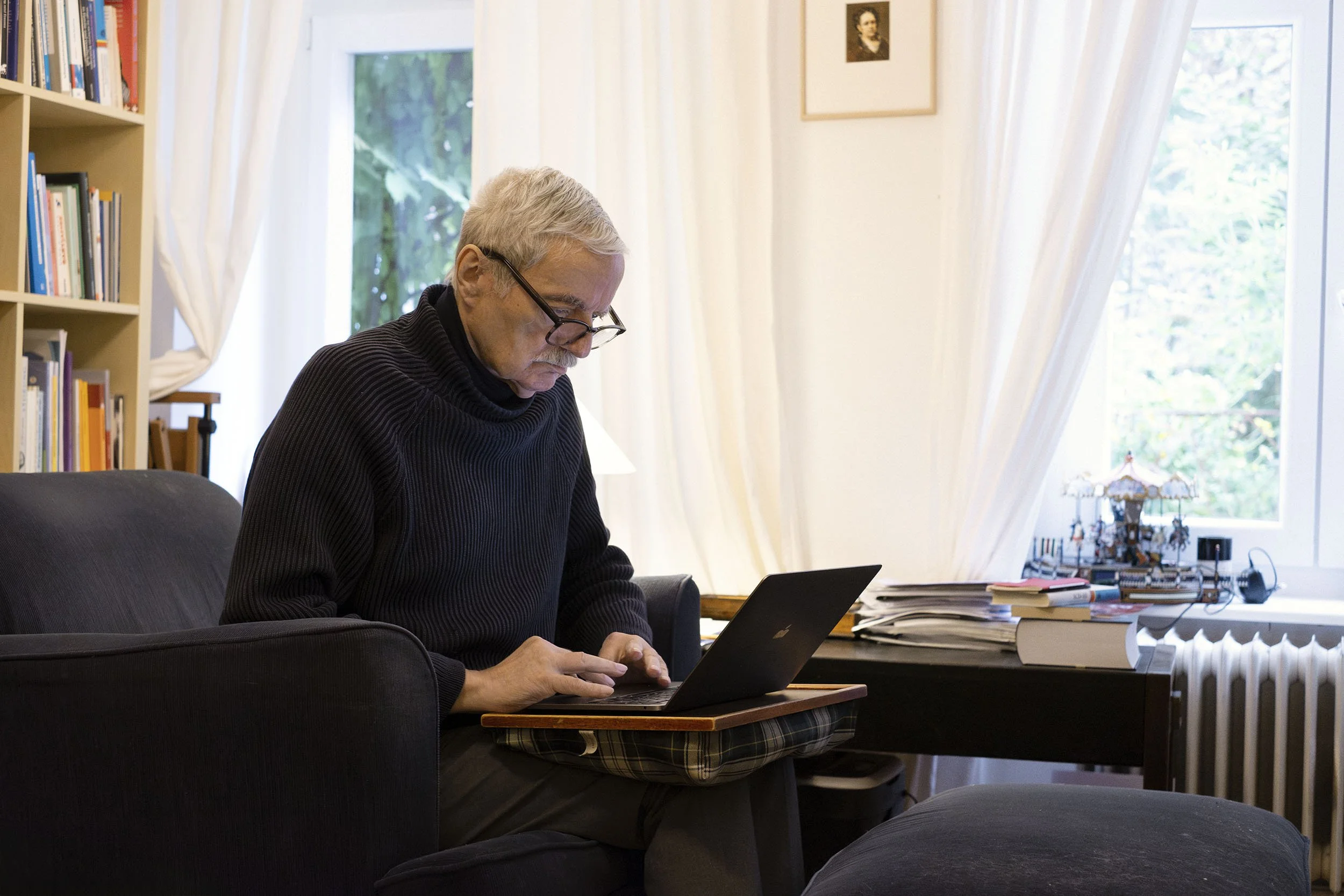 Udo Baer sitzt in seinem Arbeitszimmer, arbeitet an einem Laptop.