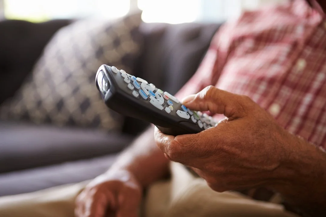 person touching a TV remote control