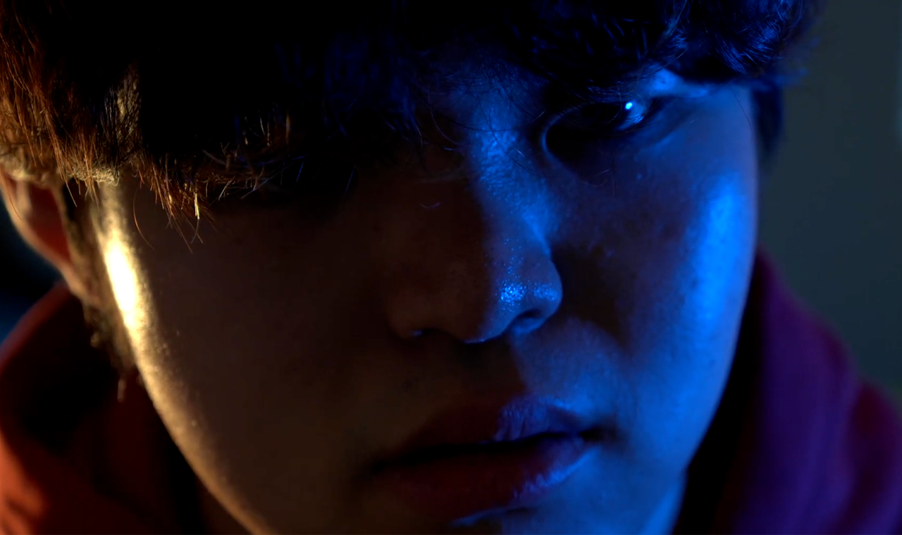 Kariena Panpaliya was the Director of Photography for Further the Past, a USC Film Student project directed by Stefano Coglitore. Close-up of a young person's face with dark hair, illuminated by blue lighting, looking down with a serious expression.