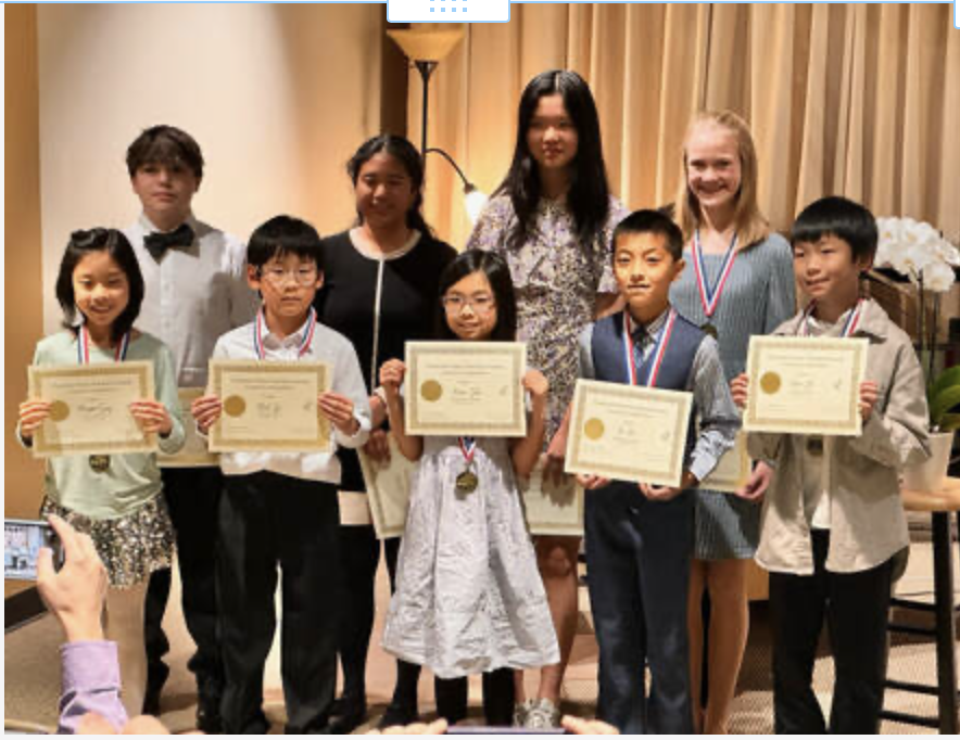 Children holding certificates and medals at an award ceremony.