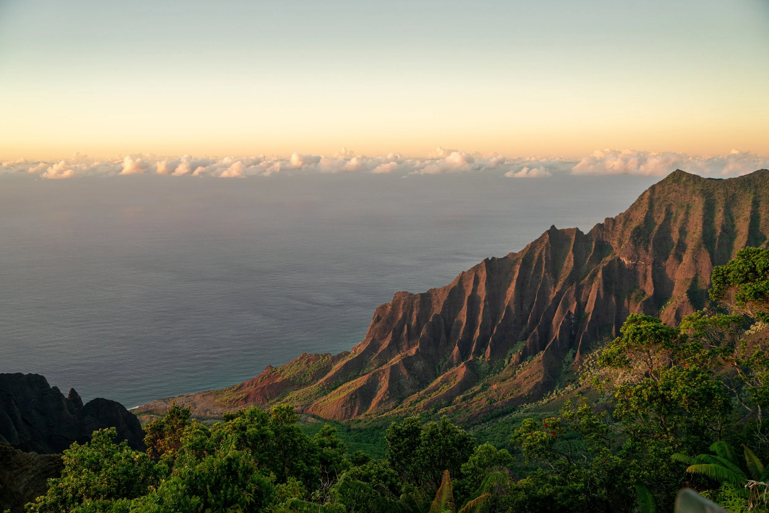Paysage de montagnes verdoyantes au bord de l'océan avec un ciel clair au coucher du soleil