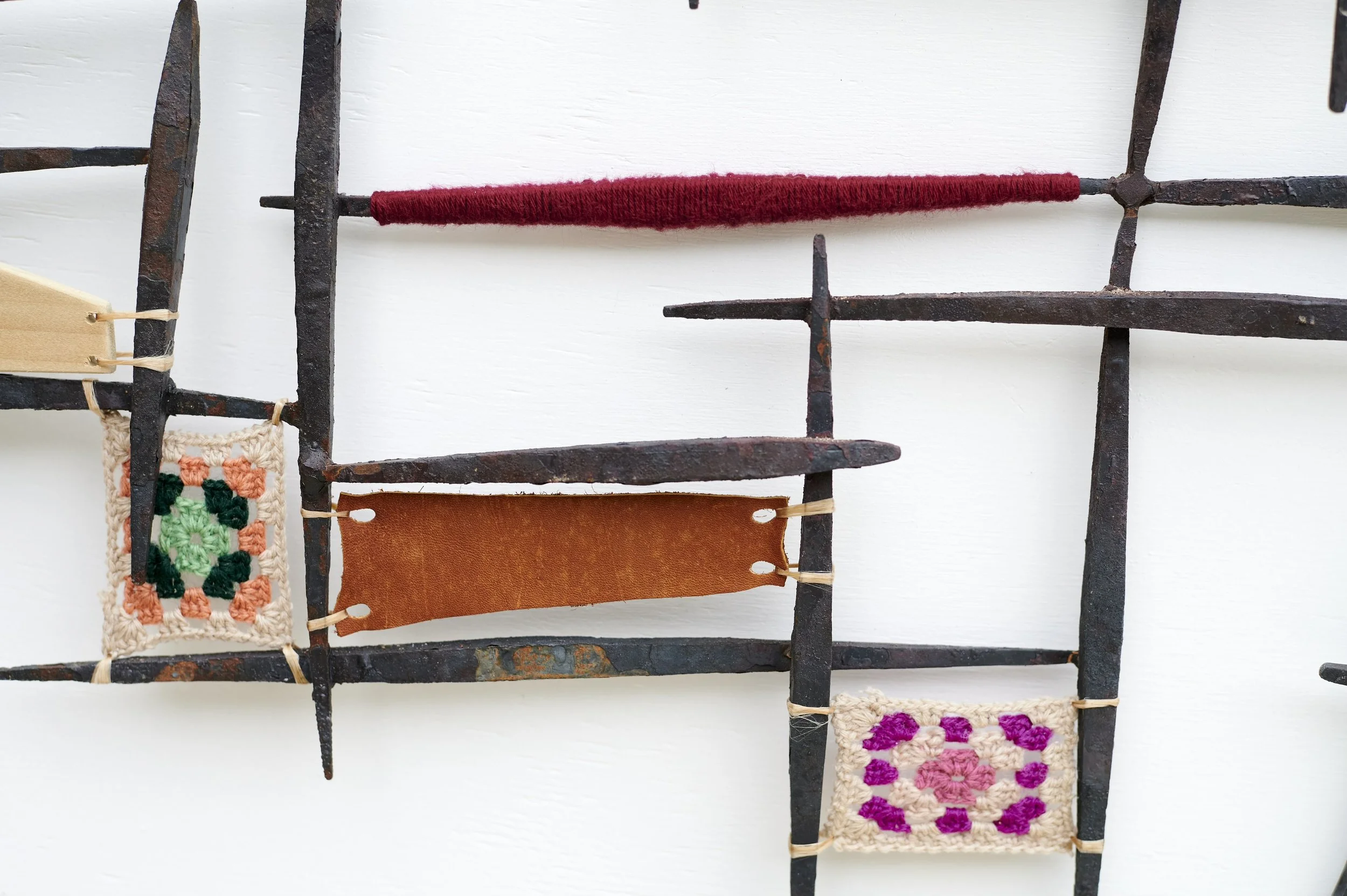 Material Reunion (detail), 2025. Salvaged metal, vintage scrap leather, crocheted granny squares, scrap wood, vintage embroidery floss.
