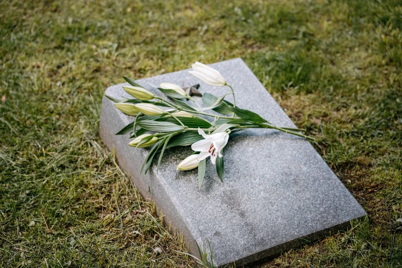 A tombstone with lilies on top