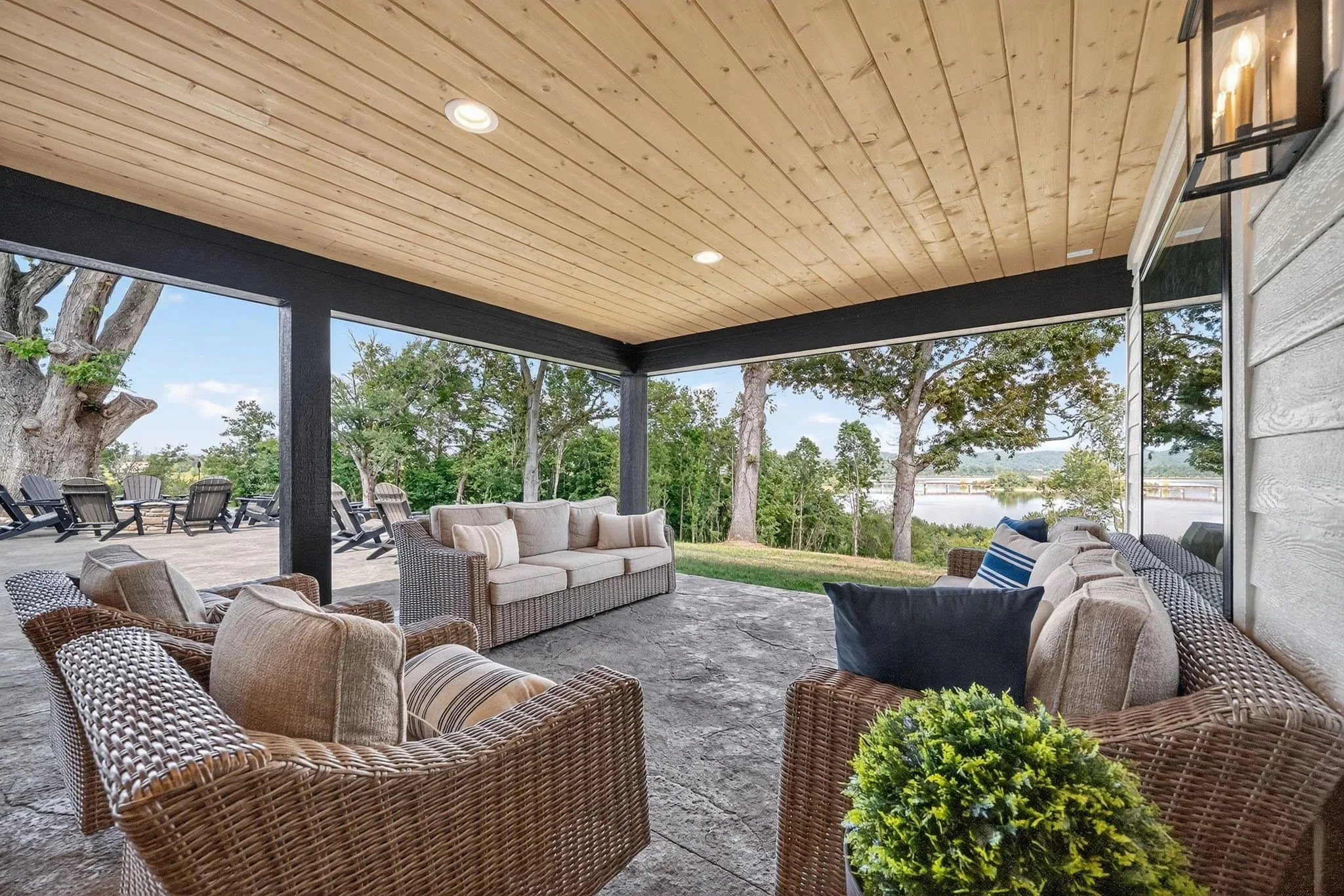 Covered outdoor patio with wicker and cushioned sofas and chairs, overlooking Douglas Lake.