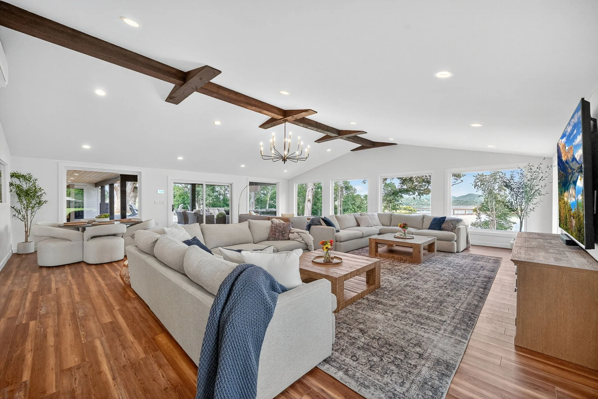 Spacious Great Room with two sectional sofas, 100" TV, and large windows overlooking Douglas Lake and train trestle.