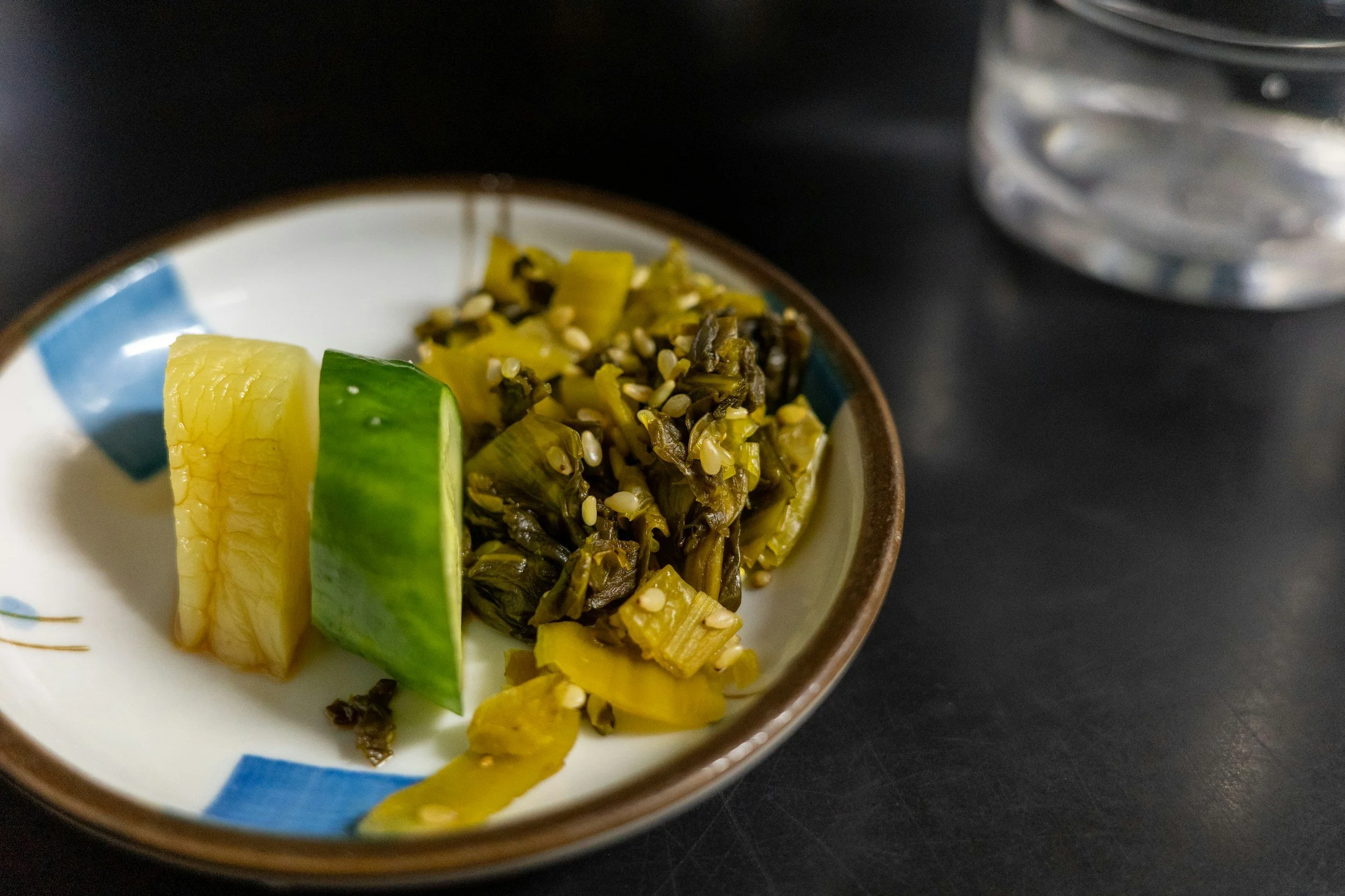A plate of Japanese pickles, including a cucumber, daikon and some mustard greens