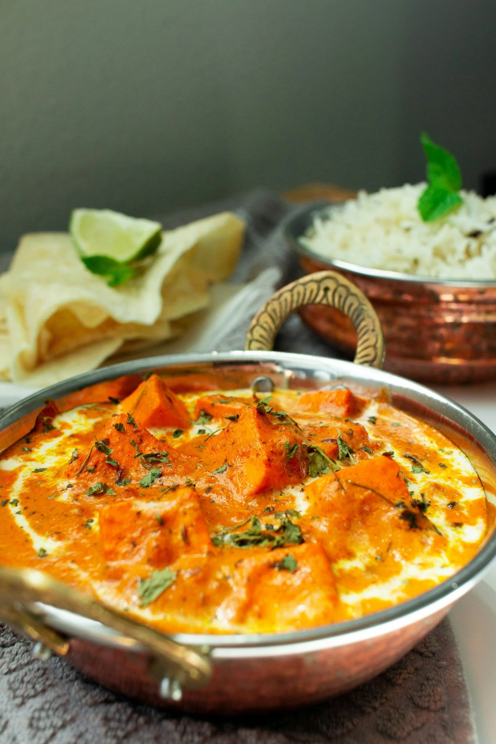 Indian curry in a metal bowl with a side of rice