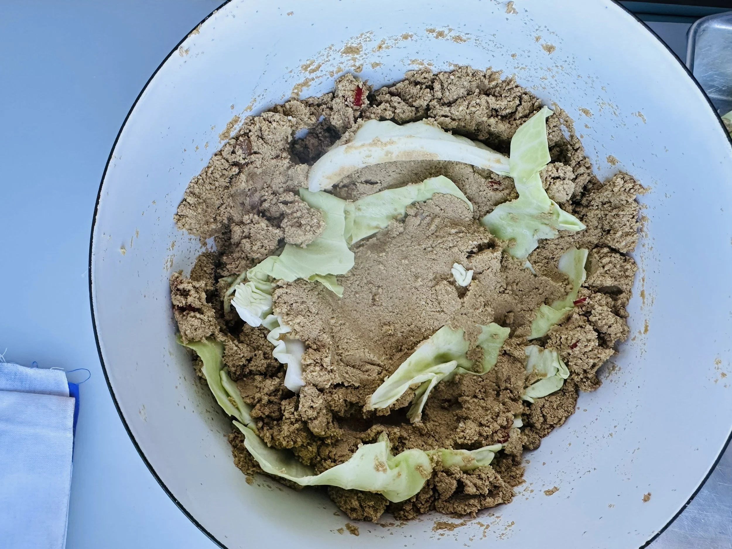 Burrying cabbage leaves in the nukadoko mixture