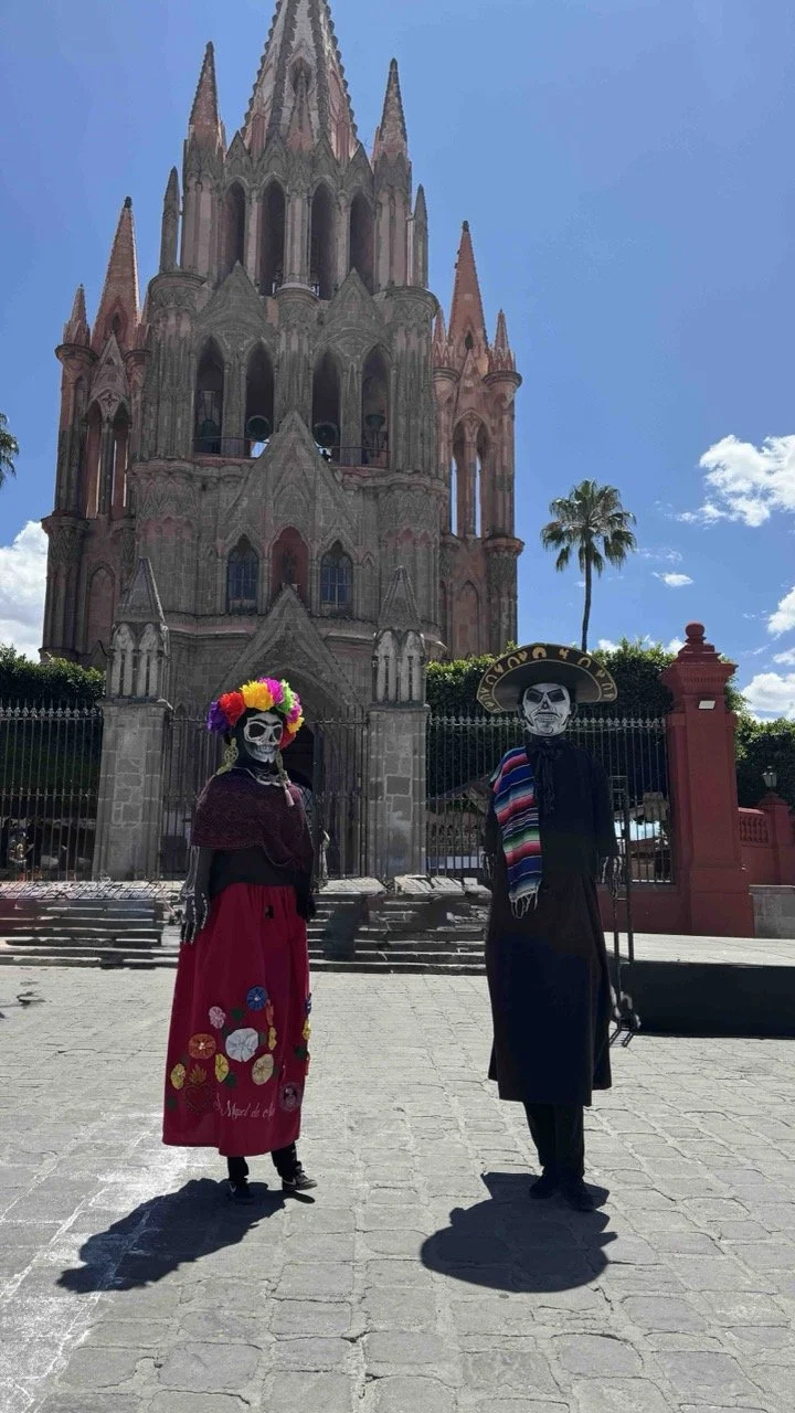 Two mujigangas  in the Jardín Principal, standing in front of La Parroquia de San Miguel Arcángel in San Miguel de Allende