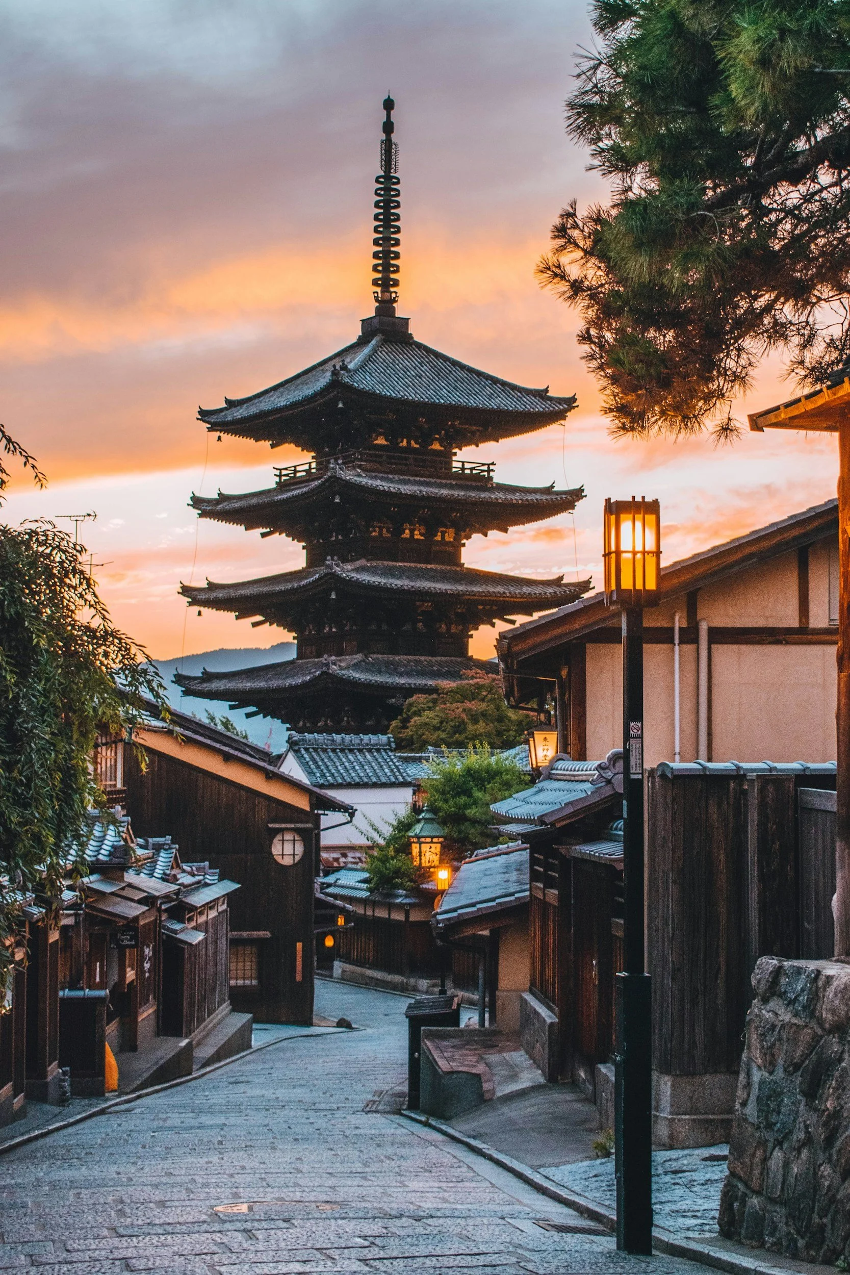 A traditional Japanese street with a five-story pagoda in the background during sunset.