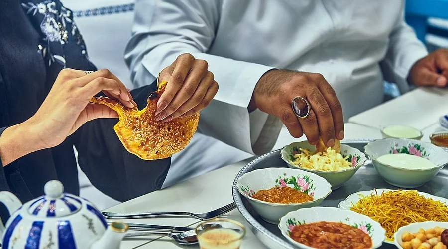 Two people sharing an Indian meal with various dishes and bread on the table.