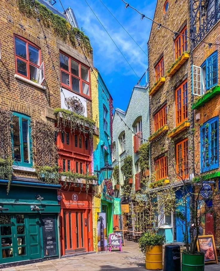 Colorful buildings with vibrant painted facades and windows in a narrow street with string lights overhead.