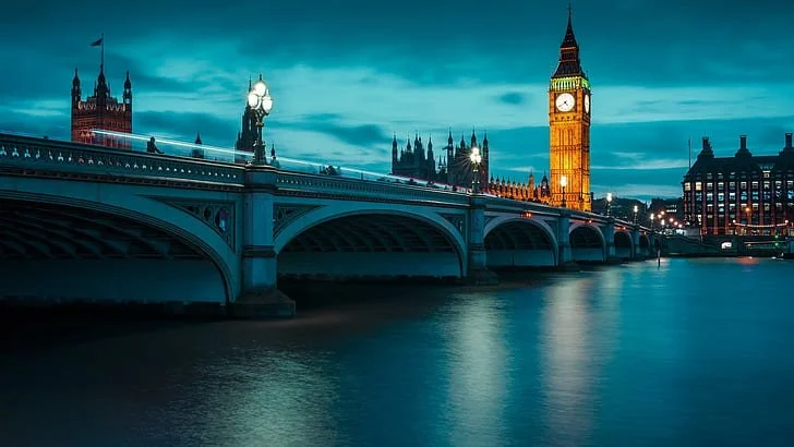 Night view of Westminster Bridge over the River Thames with Big Ben and the Houses of Parliament lit up in London, England.