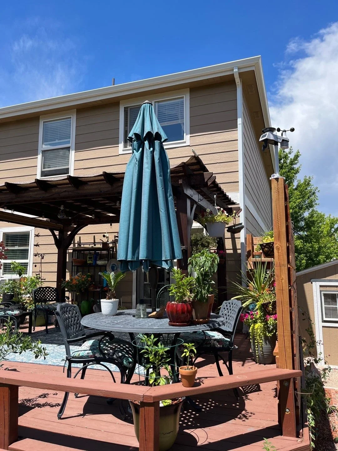 White downspout installed beside a covered backyard patio in the Denver Metro area.