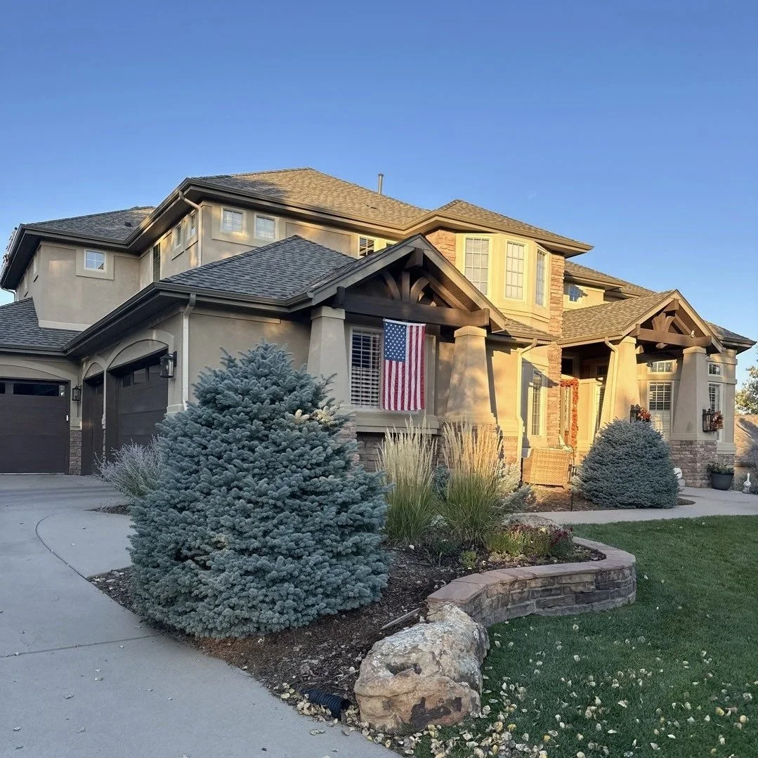Custom residential gutter installation on a large home with landscaped front grounds.