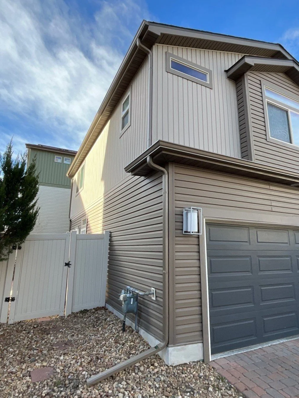 Seamless gutters and downspouts installed along the corner of a two-story home.