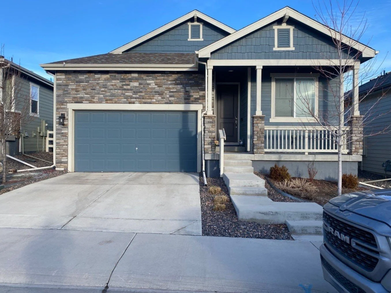 Blue and stone home with white seamless gutters and downspouts above the garage.