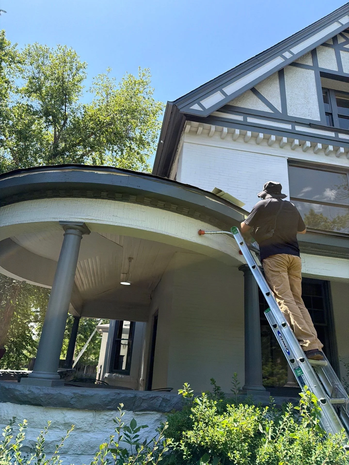 Kelly Gutter owner measuring the rounded turret roofline for precisely fitted custom gutter pieces in Congress Park, Denver.