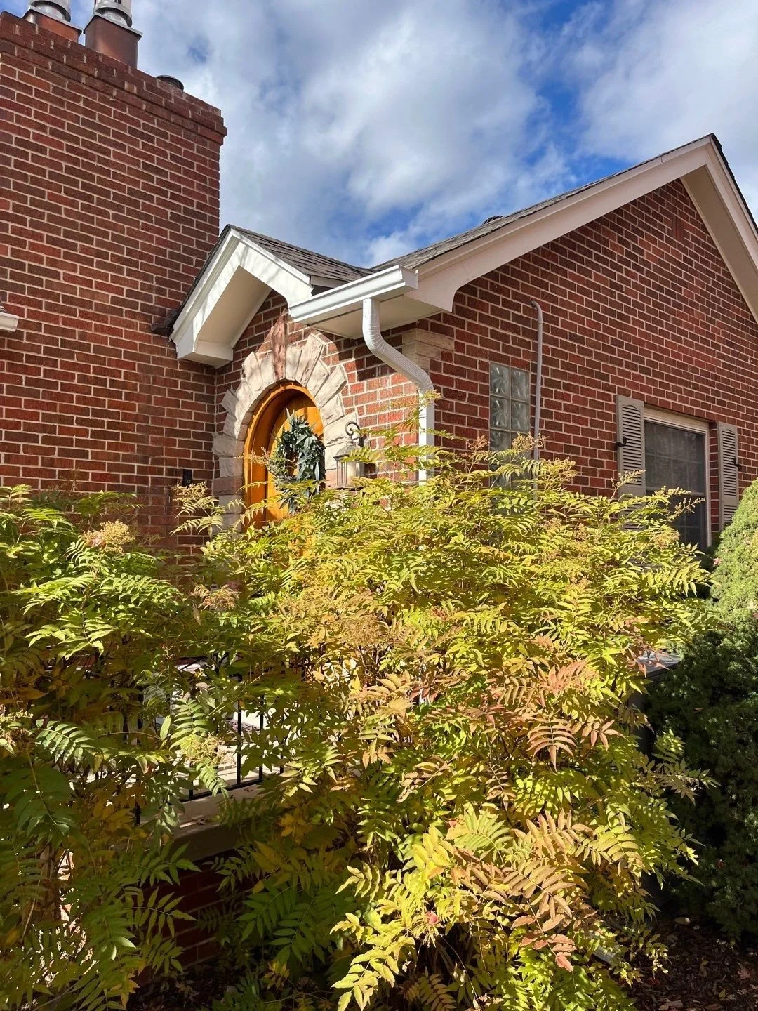 Brick home with seamless gutters and downspouts installed around the front entry.