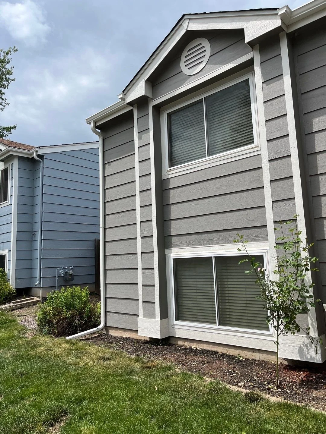 Close-up of white seamless gutters and downspouts installed on a gray-sided home.