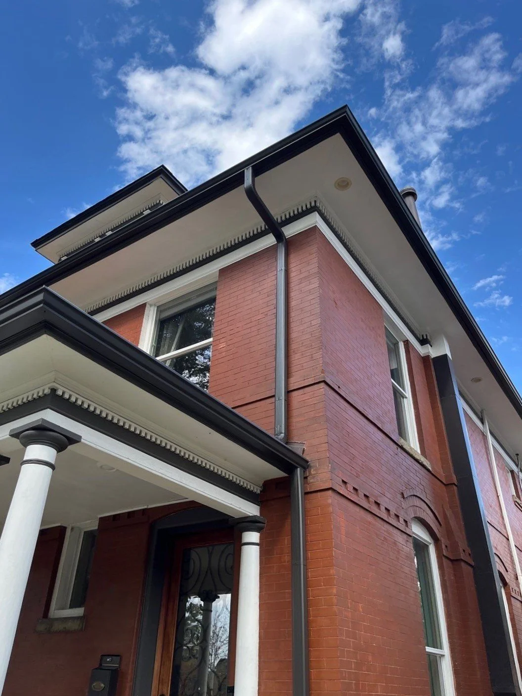 Seamless gutter system installed on a two-story brick home with a covered entry.