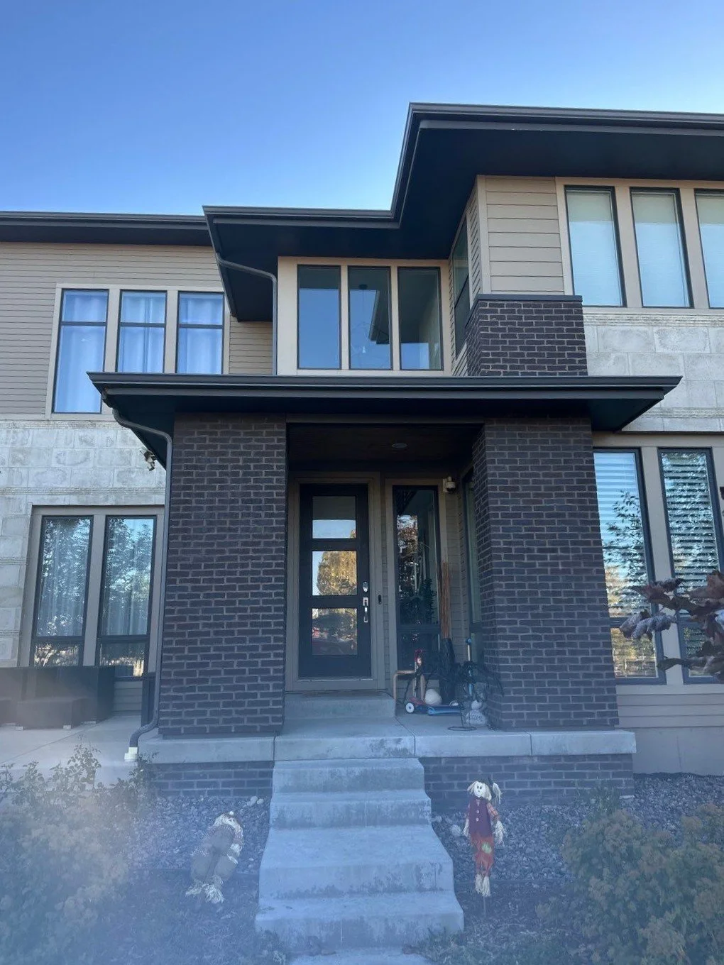 Modern two-story home with seamless gutters and downspouts around the front entry.