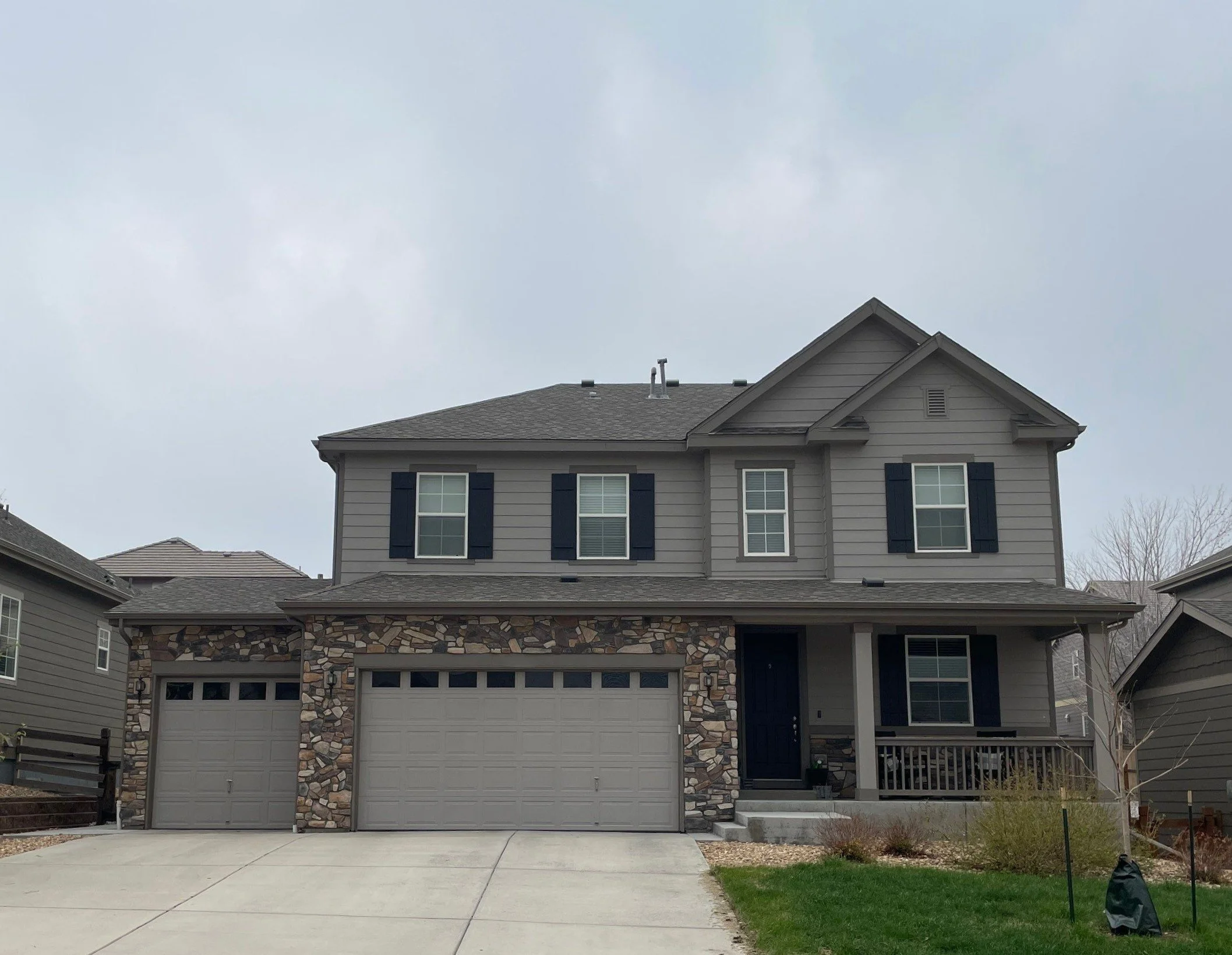 Gray two-story home with terratone seamless gutters, downspouts, and an attached three-car garage.