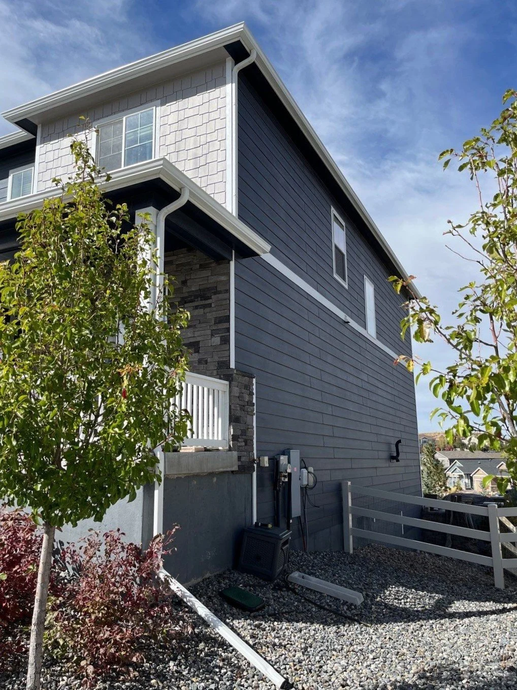 Seamless gutters and downspout installed along the side rooflines of a gray two-story home.