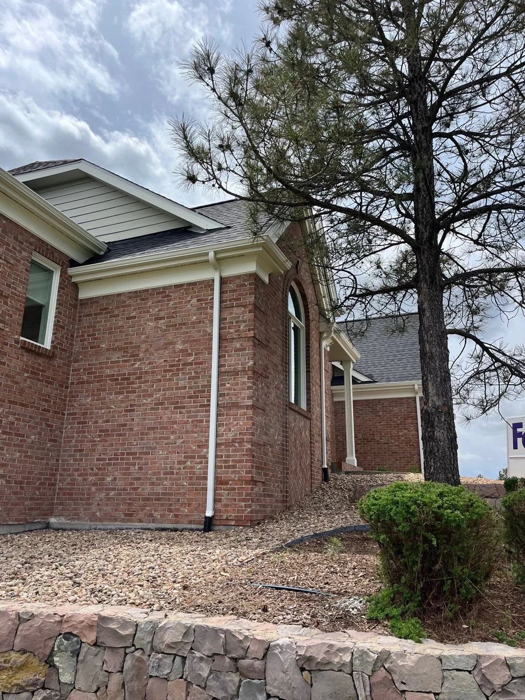 New white seamless gutter and 2×3-inch downspout installed on the brick exterior of a Bayou Hills home in Parker, CO.